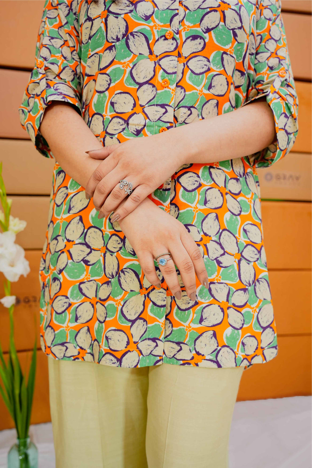 Person wearing a colorful patterned top with a wooden background
