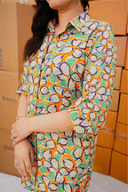 Person wearing a colorful patterned shirt in front of cardboard boxes