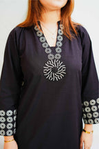 Black dress with white floral patterns on sleeves and neckline against a plain background