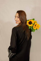 Woman holding sunflowers against a beige background