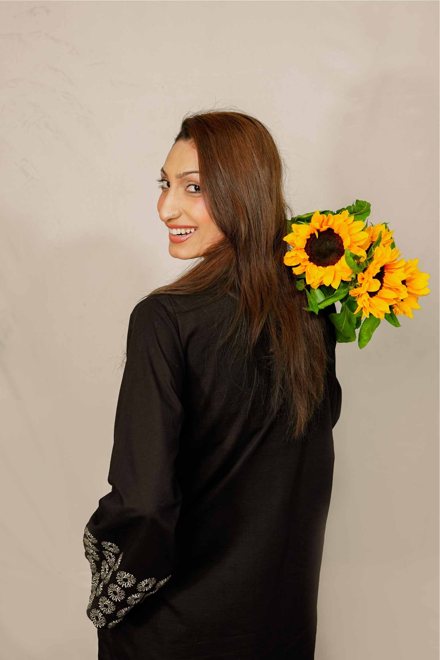 Woman holding sunflowers against a beige background