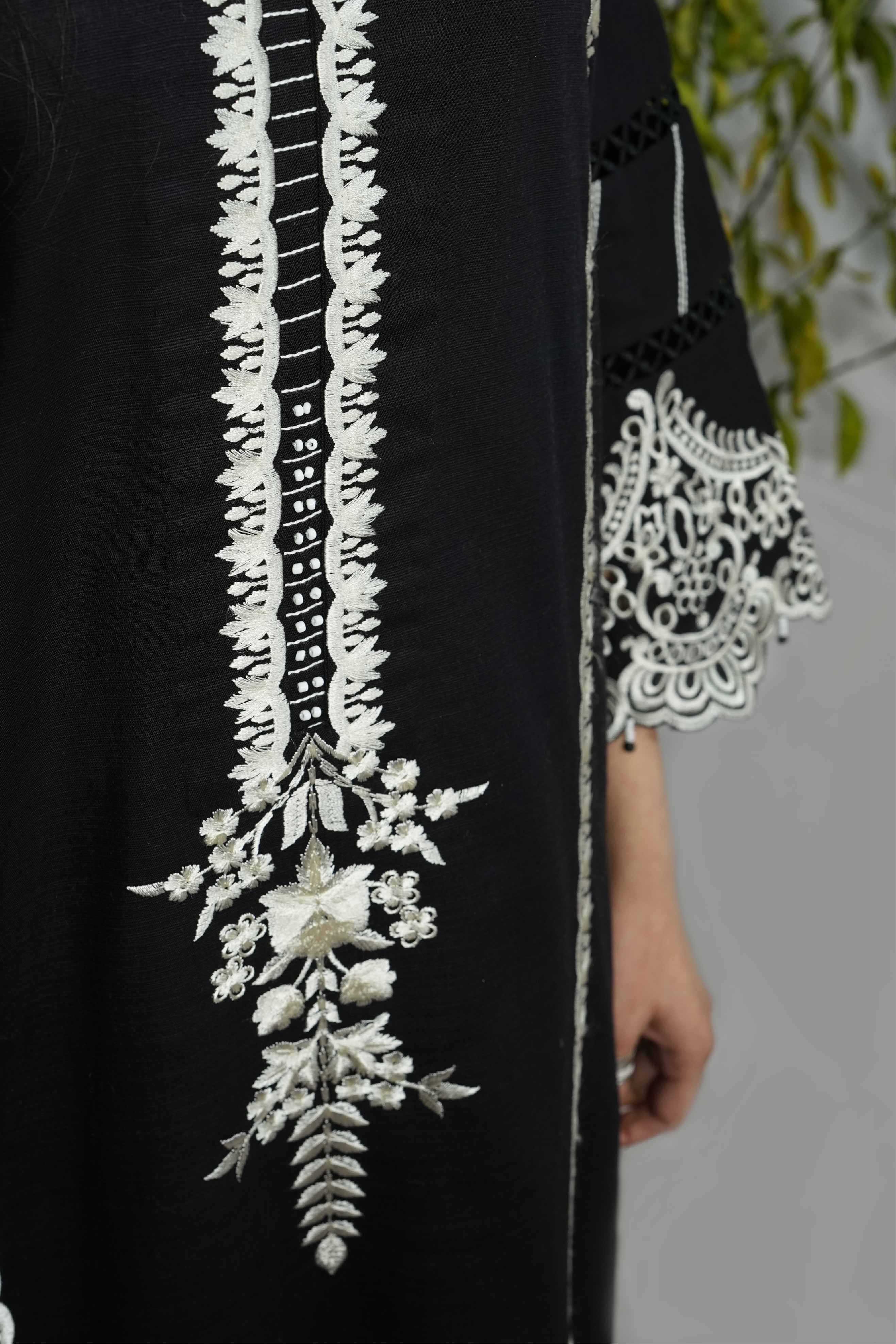 Black garment with white floral embroidery on a blurred background