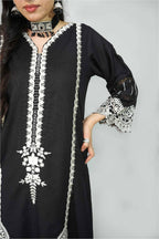 Black dress with white embroidery on a plain background