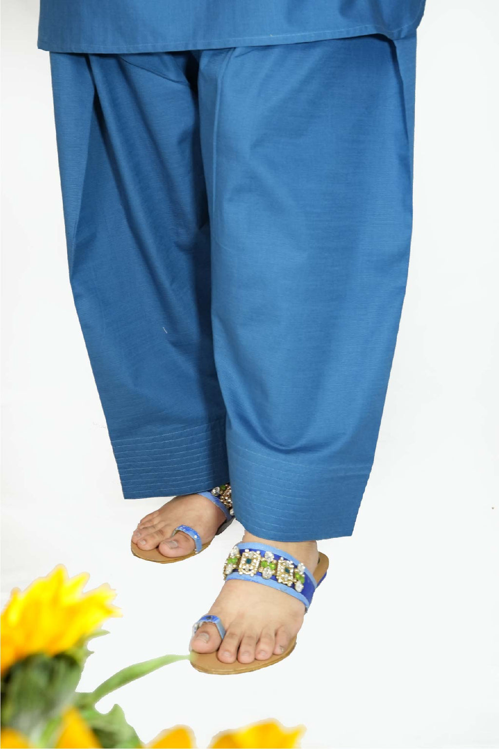 Blue pants worn by a person with sandals on a white background