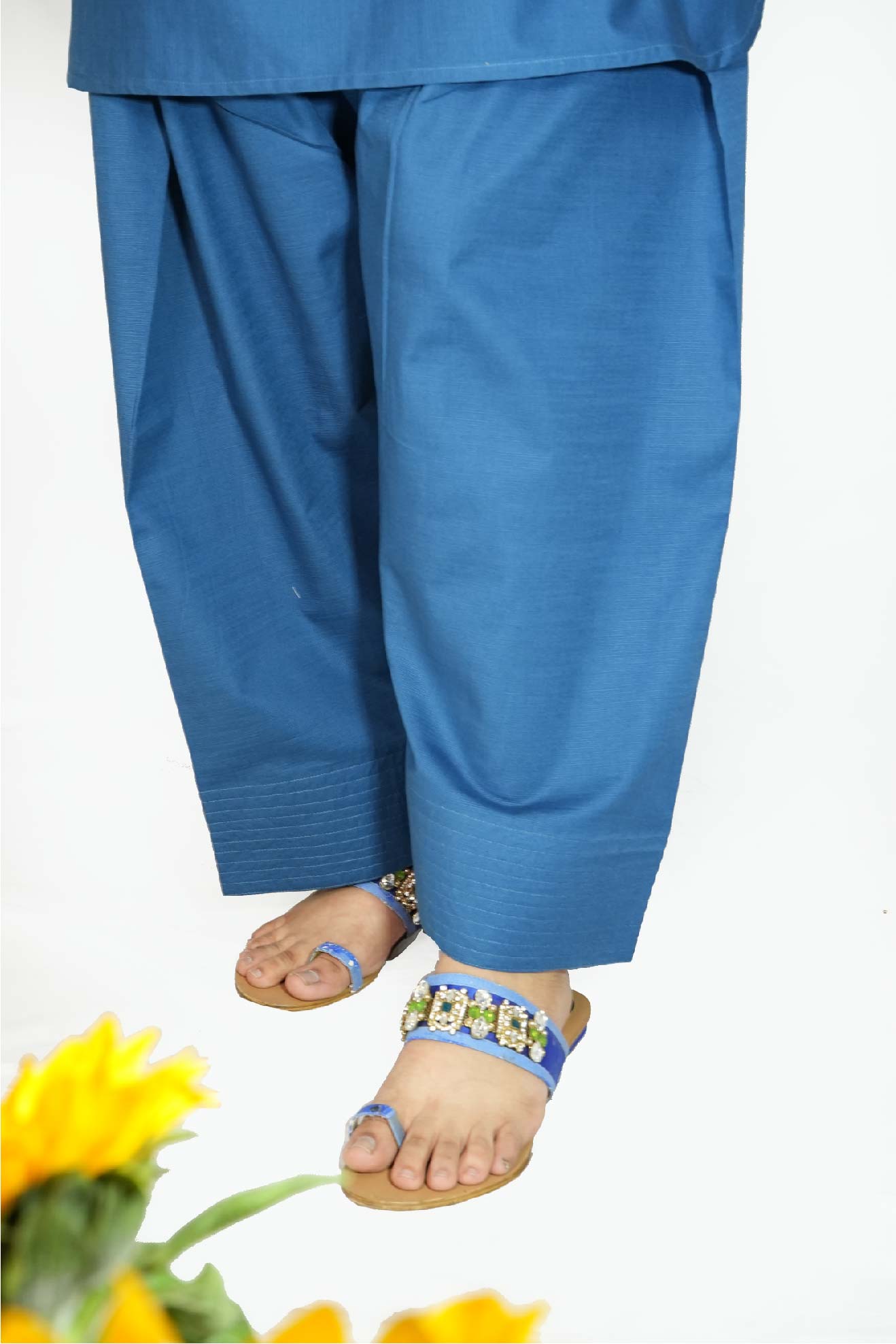 Blue pants worn by a person with sandals on a white background