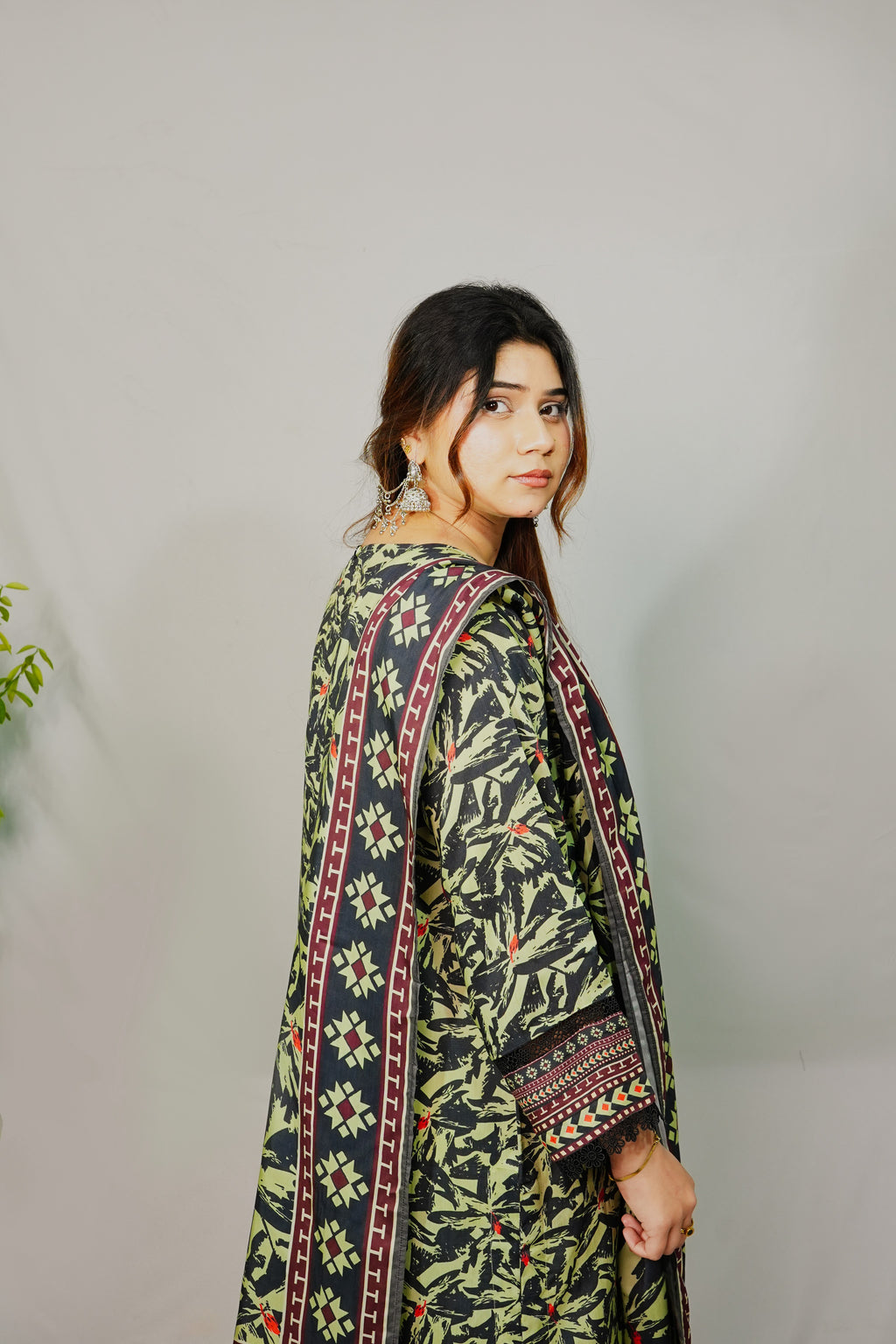 Woman wearing a traditional patterned outfit against a plain background
