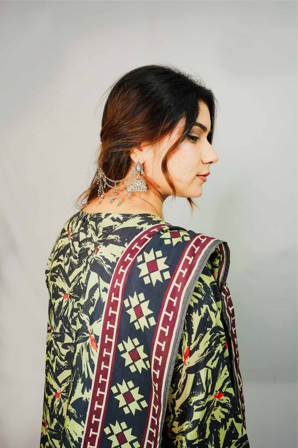 Woman wearing a patterned saree with a plain background