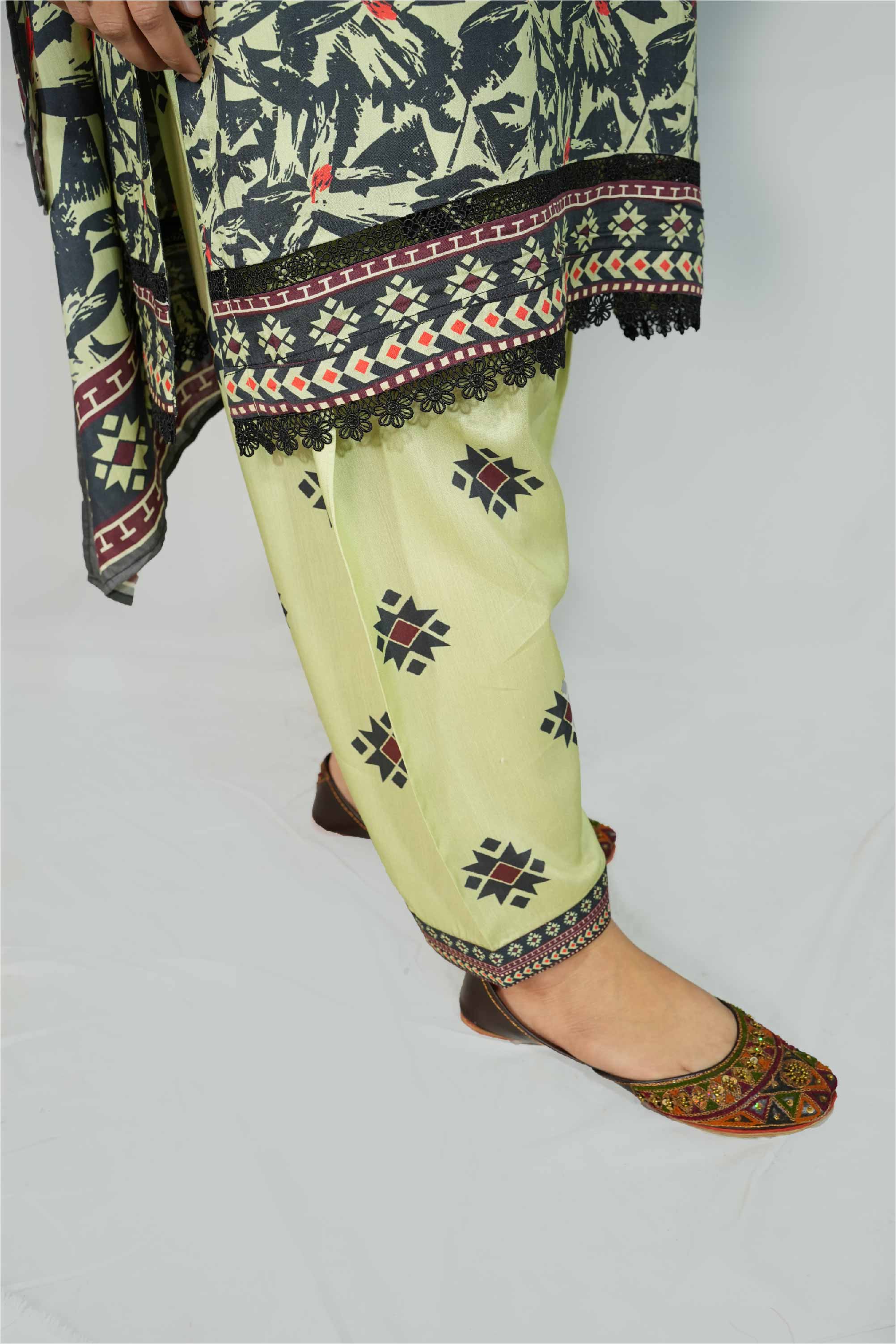 Traditional outfit with a patterned top and light green pants on a plain background
