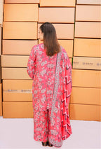 Woman in a pink floral outfit standing in front of stacked boxes.