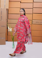 Woman in a red floral outfit standing in front of stacked cardboard boxes.