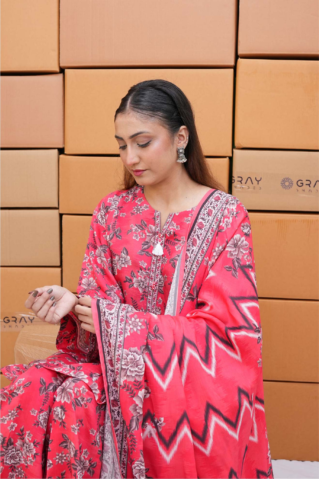 Woman in a red floral dress sitting in front of cardboard boxes with 'Gray' branding.