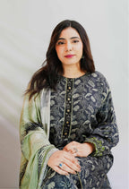 Woman wearing a dark floral dress with a light green dupatta against a plain background