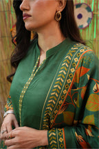 Woman wearing a green traditional outfit with intricate patterns and embroidery.