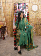 Woman in a green traditional outfit sitting on a decorative chair with a colorful quilt in the background.
