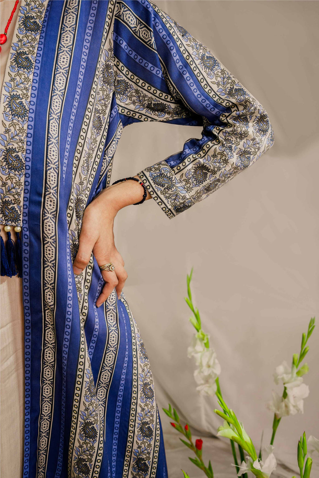 Close-up of a person wearing a blue and silver embroidered traditional outfit with a neutral background.