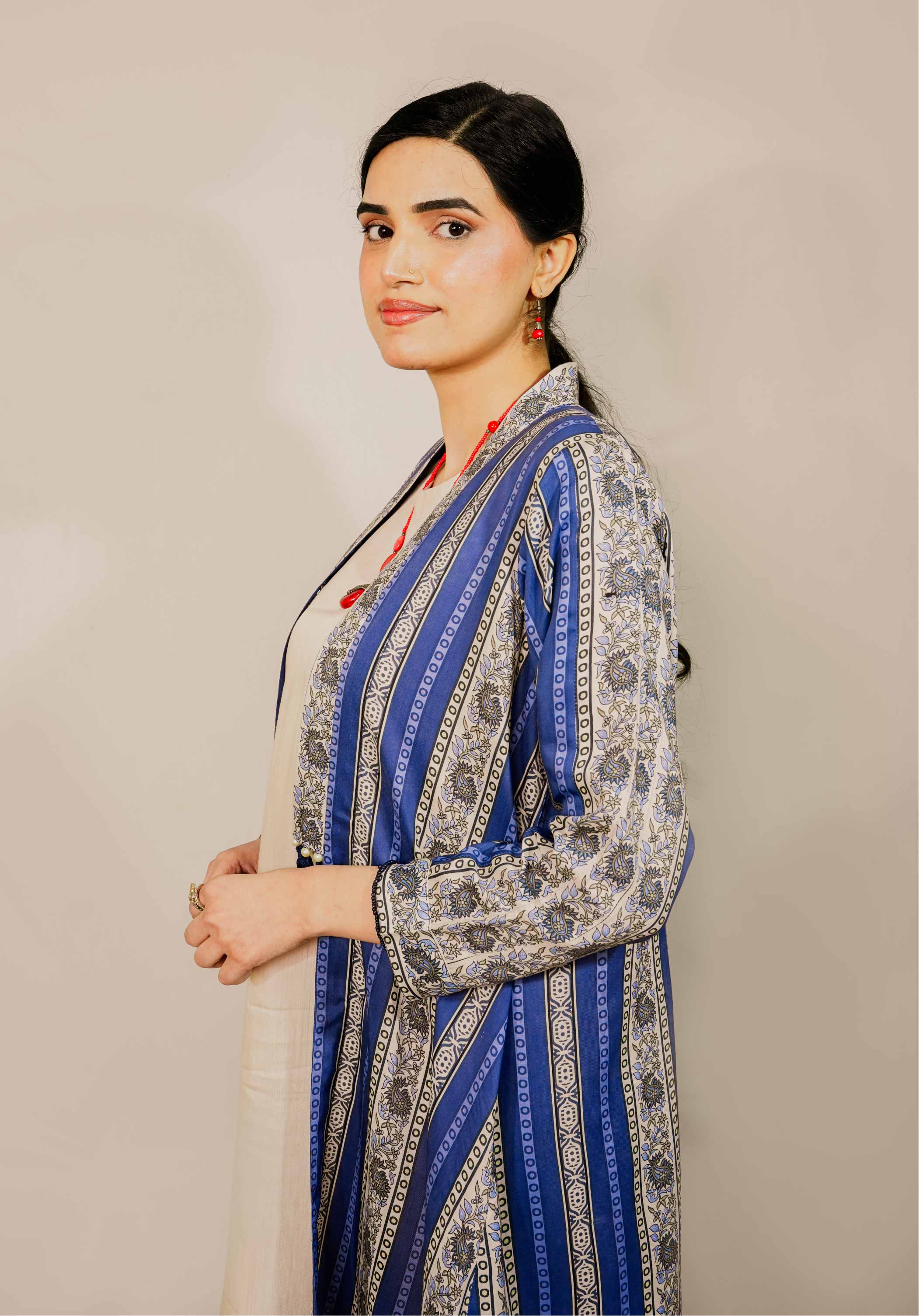 Woman wearing a blue and gray patterned dress against a beige background