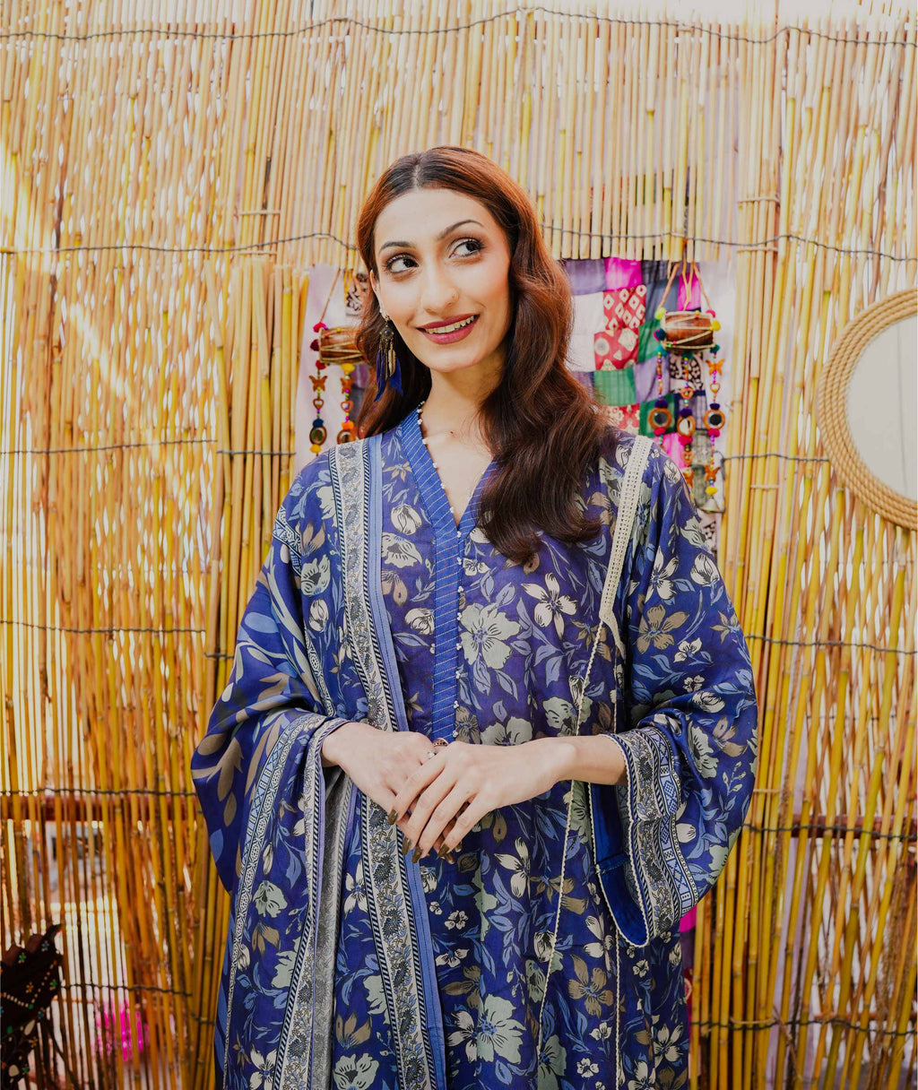 Woman in a blue patterned dress standing against a decorative background
