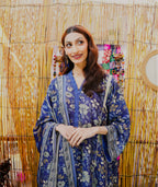 Woman in a blue patterned dress standing against a decorative background