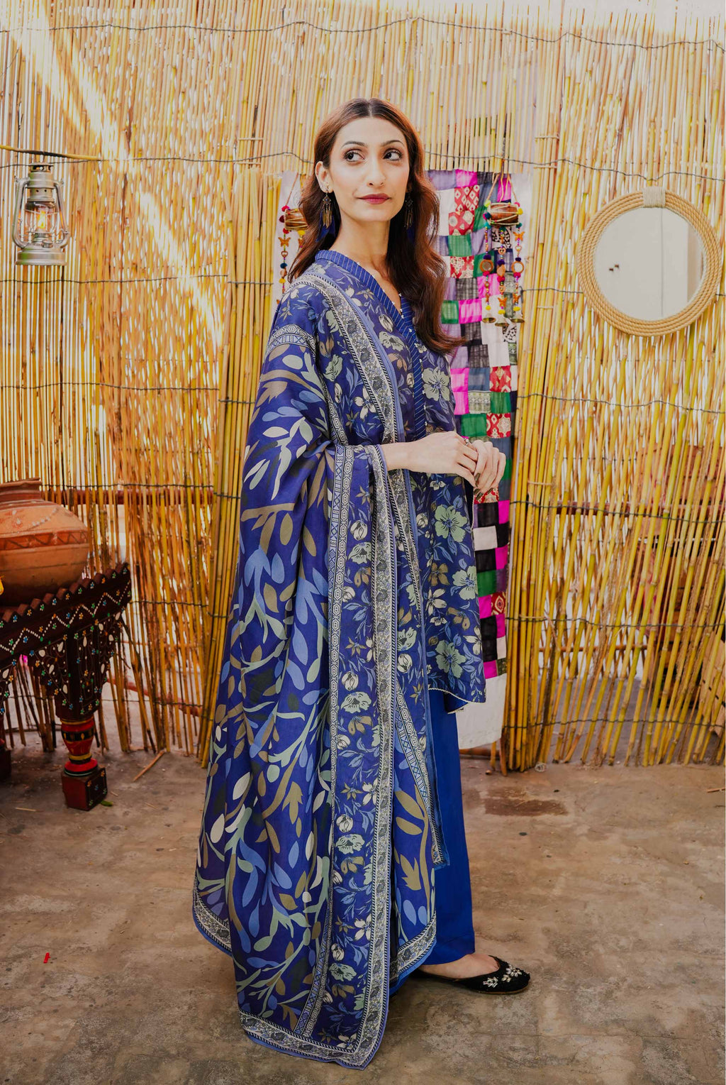Woman wearing a blue patterned dress standing in front of a decorative wall.