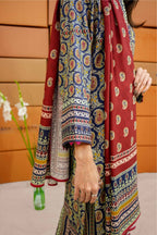 Colorful patterned fabric with a person wearing it, against a wooden panel background.