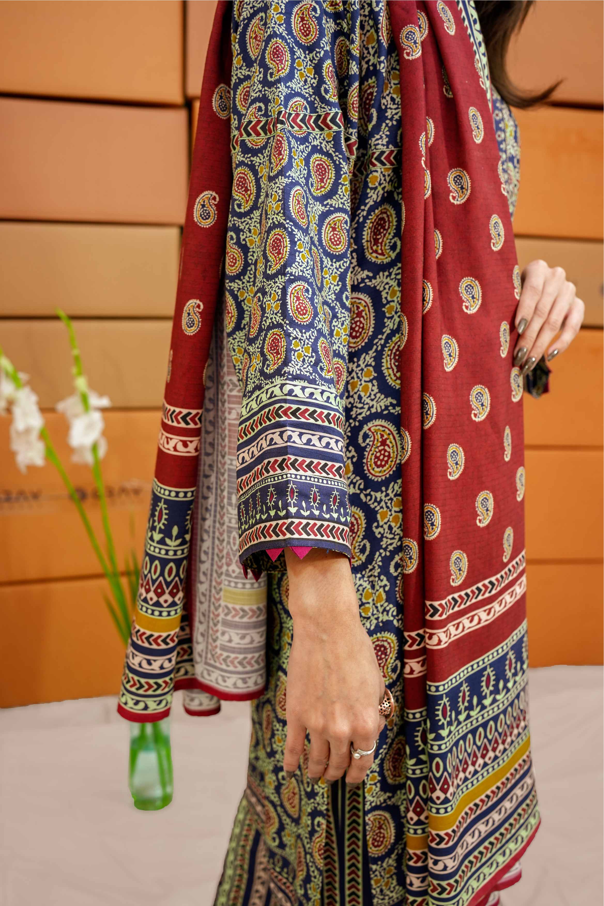 Colorful patterned fabric with a person wearing it, against a wooden panel background.