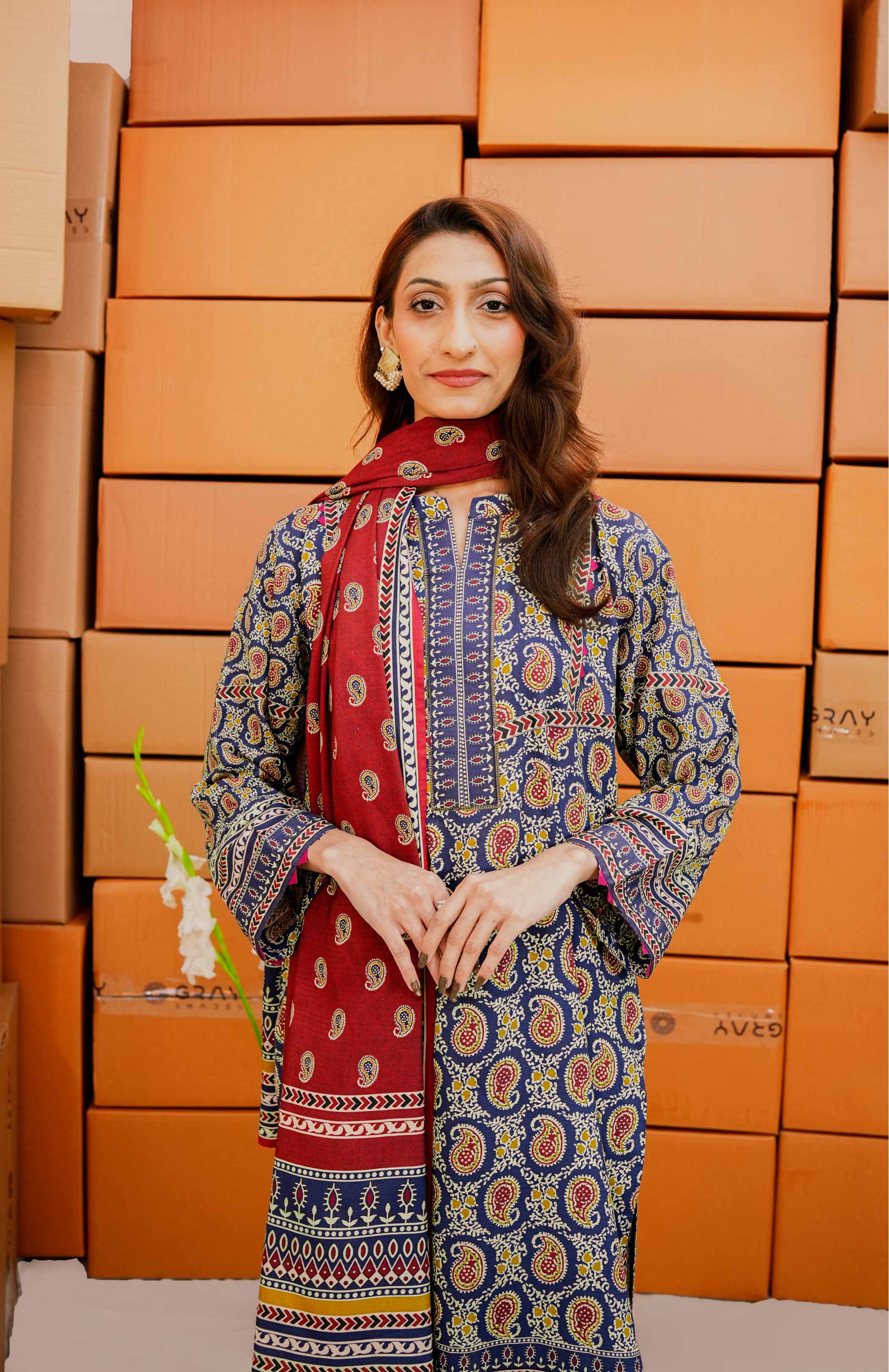 Woman in a patterned outfit standing in front of stacked boxes