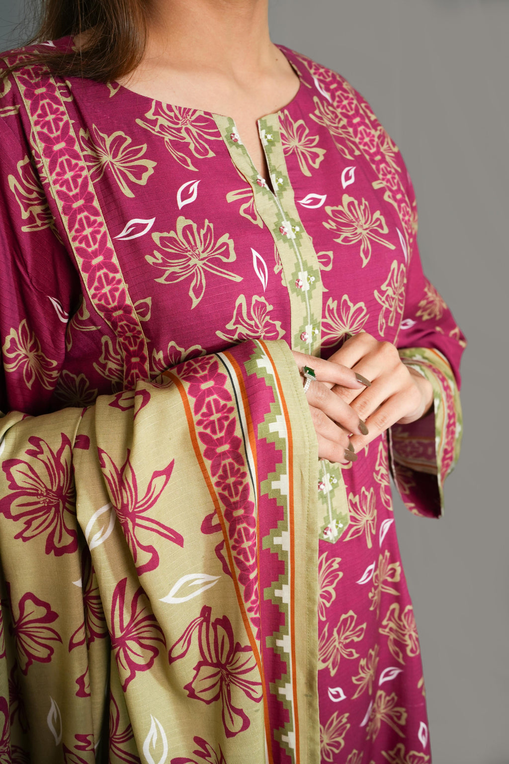 Traditional outfit with pink and green floral patterns on a plain background