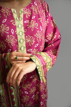 Close-up of a person wearing a pink traditional outfit with floral patterns on a gray background