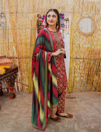 Woman in a colorful traditional outfit standing in front of a bamboo wall.