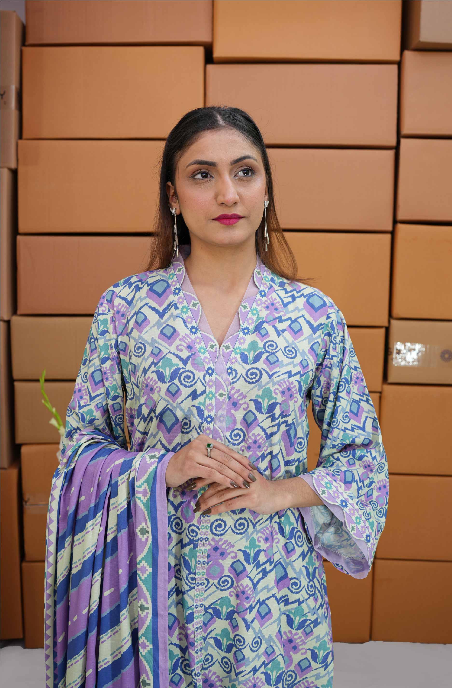 Woman in a patterned outfit standing in front of stacked boxes