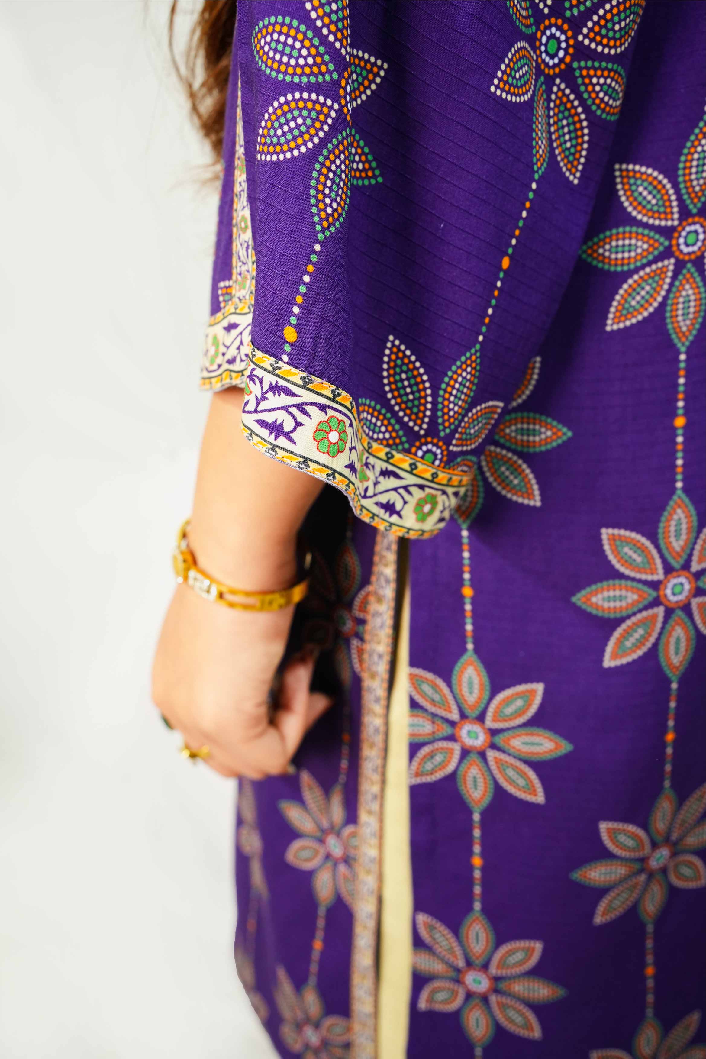 Purple fabric with floral patterns and gold trim, held by a person.