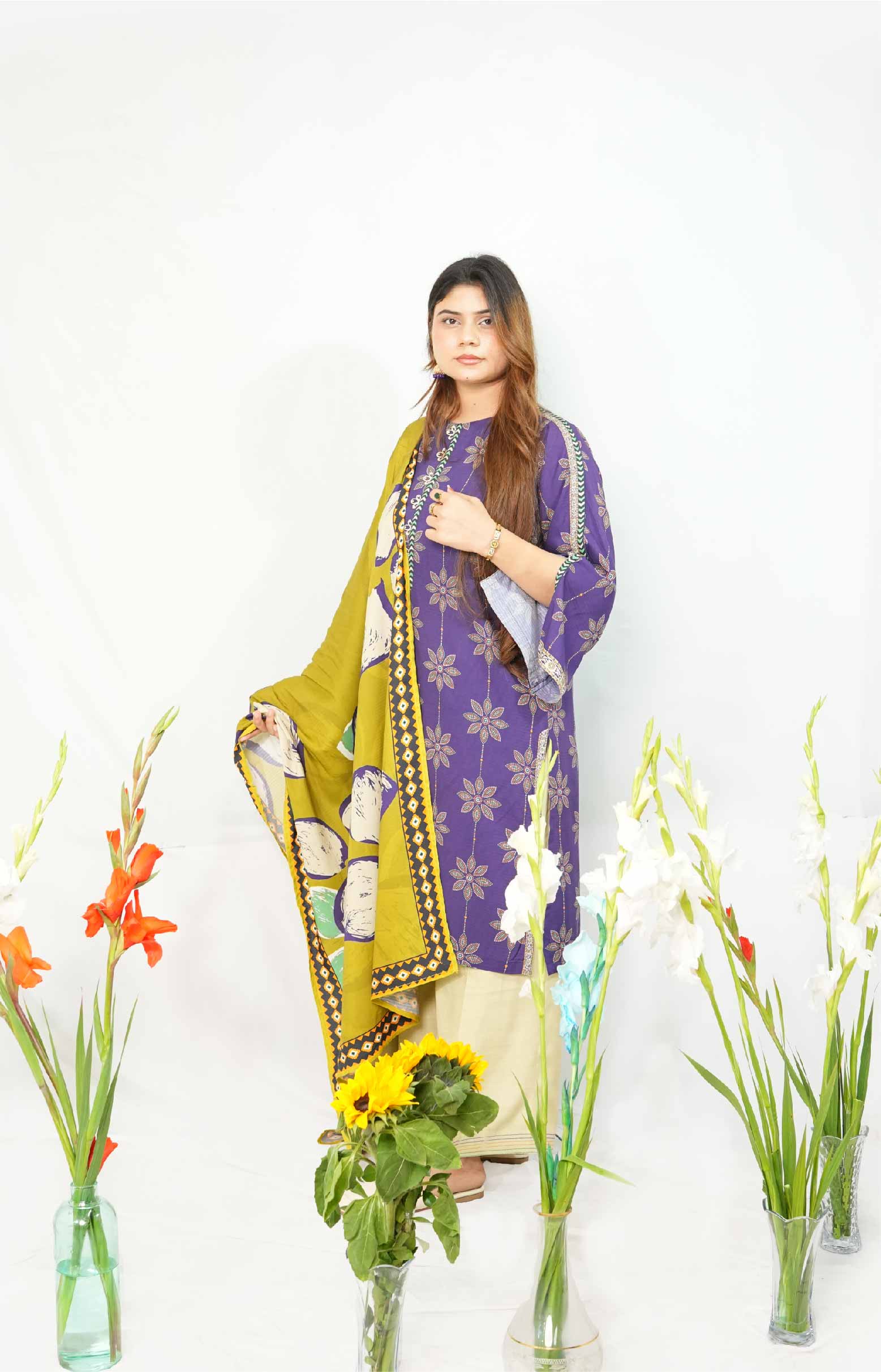 Woman in a purple and yellow traditional outfit with floral arrangements on a white background