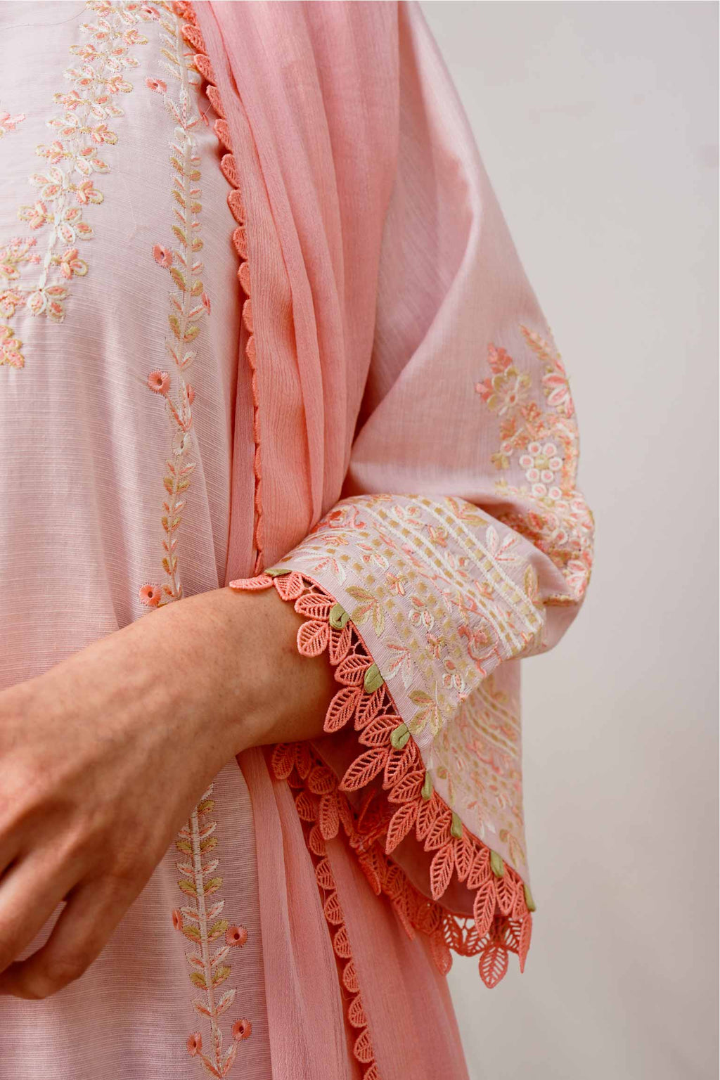 Close-up of a pink embroidered garment with floral patterns on a plain background