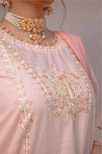 Close-up of a pink embroidered garment with intricate designs and jewelry.