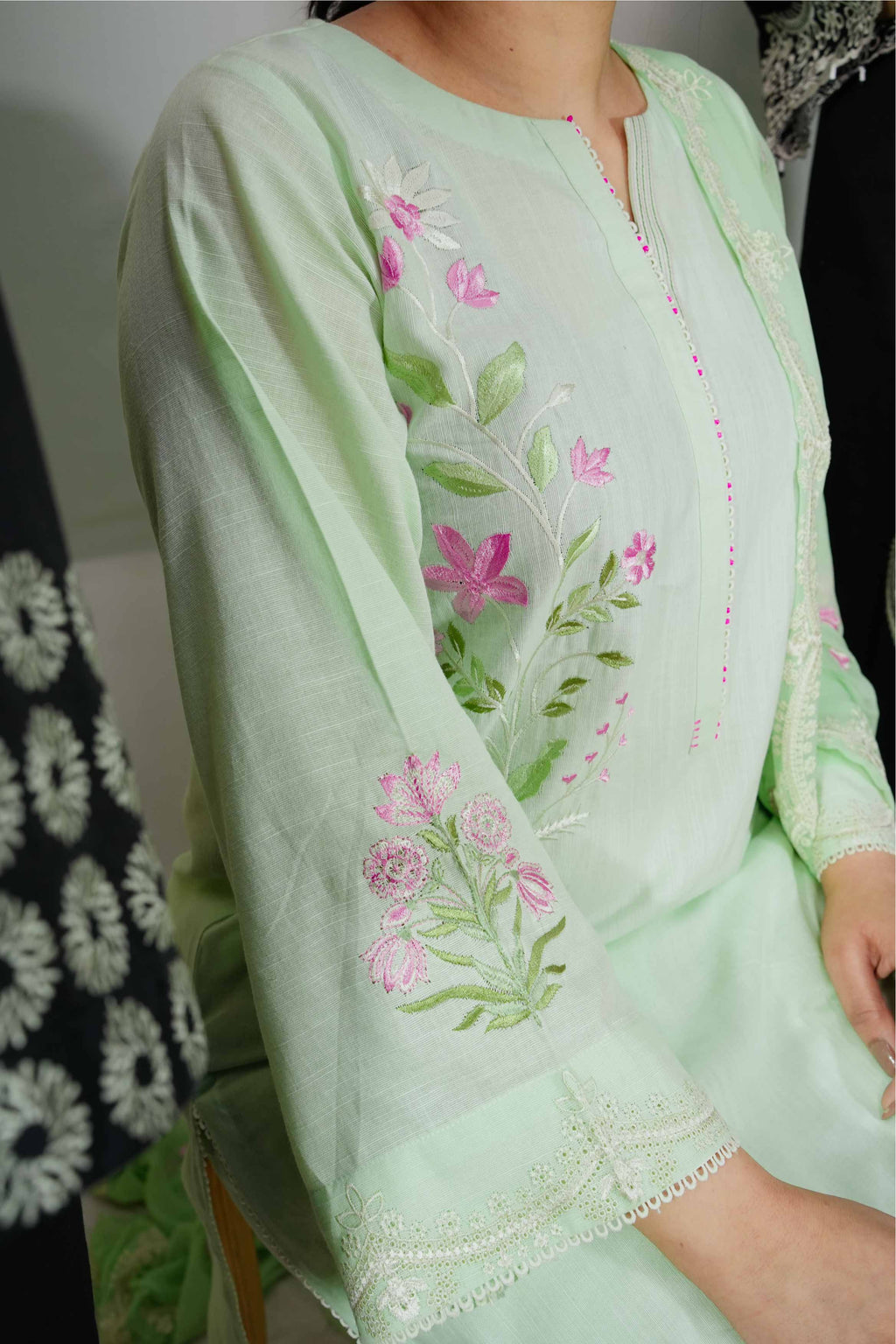 Light green embroidered dress with pink flowers on a plain background